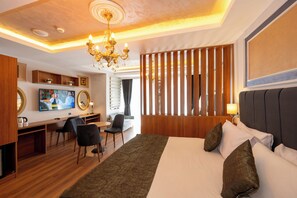 Ein Hotelzimmer mit einem großen Bett, einem Schreibtisch mit Fernseher, einer Chandelüster und einer Holzwand.