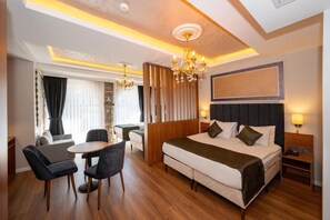 A hotel room with a large bed, a desk with chairs, a chandelier, a headboard with a lamp, and a view of the outdoors. - Harmony Istanbul (Istanbul)