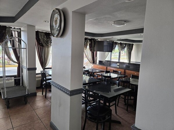 A restaurant with a bar area, tables, chairs, and a clock on the wall. - Super 8 Fort Myers Hotel (Fort Myers)