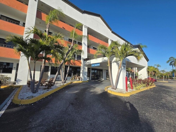 A multi-story hotel with a white facade, orange accents, and palm trees in the foreground. - Super 8 Fort Myers Hotel (Fort Myers)