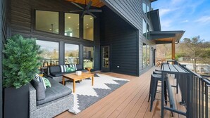 Ein modernes Haus mit einer Terrasse, einem Deckenventilator und einem großen Fenster.