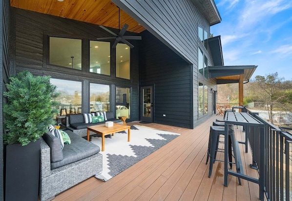 Une maison moderne dotée d’une terrasse, d’un ventilateur de plafond et d’une grande fenêtre.