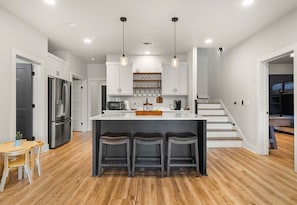 A modern kitchen with a central island, bar stools, and pendant lighting. - Private Pool, Dock, Movie Room on Lake Hamilton (Hot Springs)