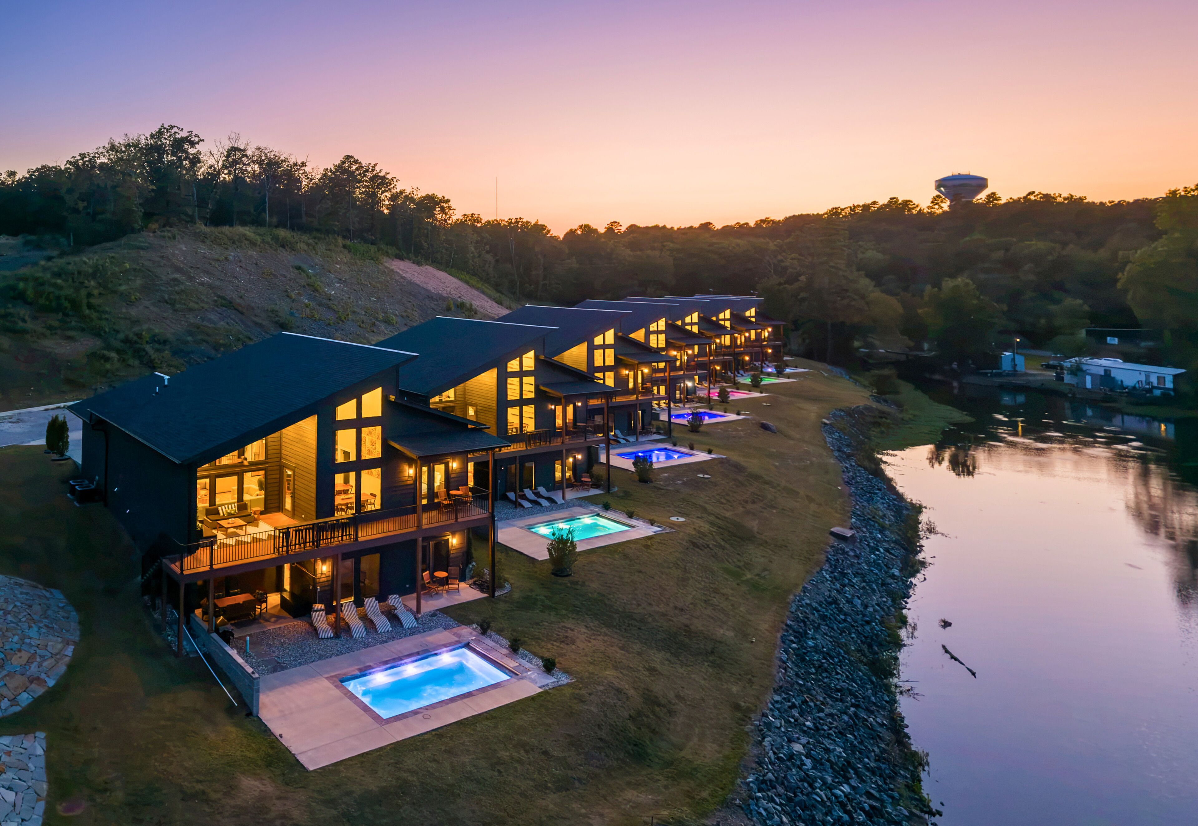 A modern multi-story house with a swimming pool and a view of a lake.