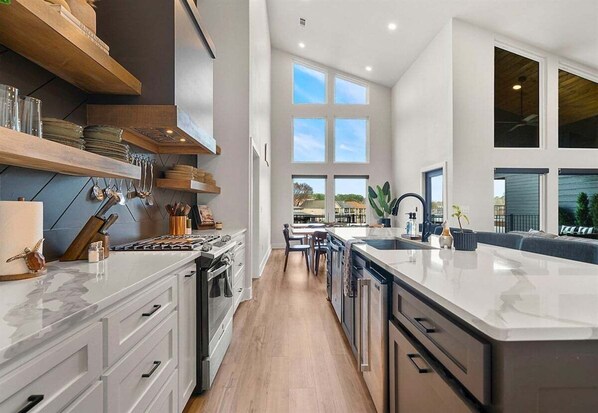 A modern kitchen with a central island, built-in appliances, and a view to the outdoors. - Private Pool, Dock, Movie Room on Lake Hamilton (Hot Springs)