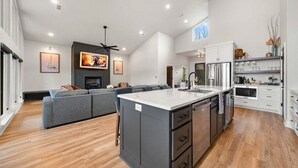 Eine moderne Küche mit einer großen Kochinsel, weißen Schränken und einem Essbereich mit einem grauen Sofa.