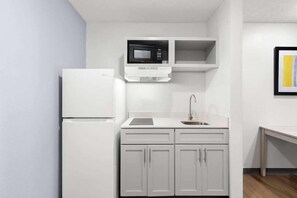 A compact kitchenette with a white refrigerator, a microwave, a sink, and a small countertop. - Suburban Studios Lakeland North I-4 (Lakeland)