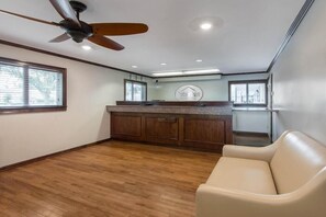 Un'ampia stanza con ventilatore a soffitto, angolo cottura con pensili in legno e divano beige.