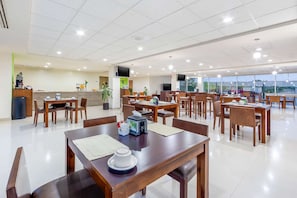 A spacious hotel dining area with multiple tables and chairs, a reception desk, and a large window offering a view. - Hotel Torreon (Torreón)