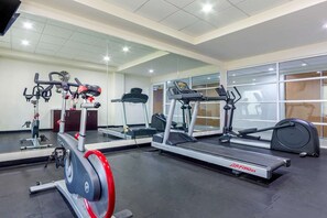 A gym with various exercise equipment including treadmills, stationary bikes, and a rowing machine. - Hotel Torreon (Torreón)