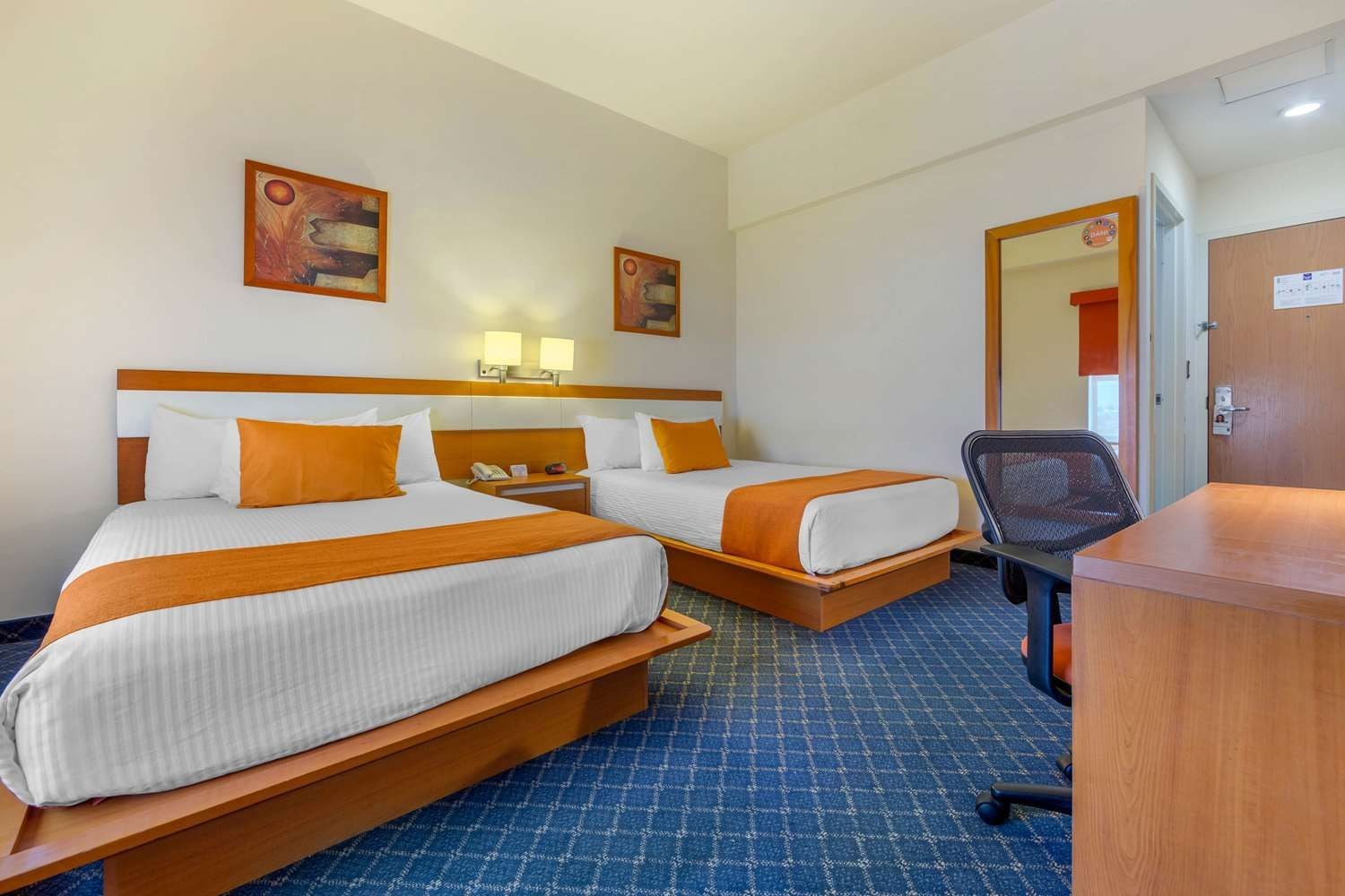 Habitación de hotel con dos camas, un escritorio y una silla.