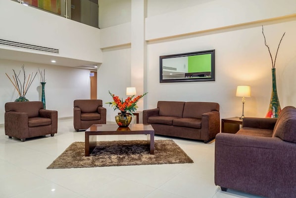 A modern living room with a flat-screen TV, two sofas, a coffee table, and decorative vases.