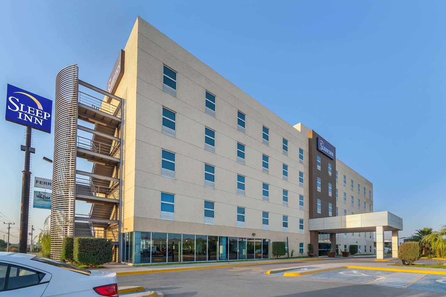 Ein Sleep Inn Hotel mit modernem Design, das eine glatte Fassade, viele Fenster und einen Parkplatz zeigt.