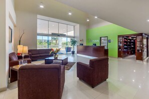 A hotel lobby with a reception desk, seating area, and a green accent wall. - Hotel Torreon (Torreón)