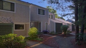 A row of two-story townhouses with a covered driveway and small front yard landscaping.