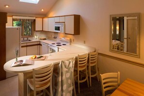 A compact kitchen with a central island, a dining area with chairs, and a mirror on the wall. - South Cape Resort (Mashpee)