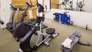 A gym with treadmills, an elliptical, a weight bench, and a mirror.