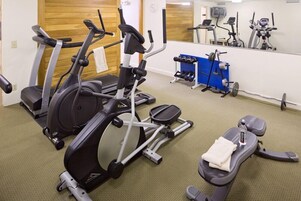 A gym with treadmills, an elliptical, a weight bench, and a mirror.