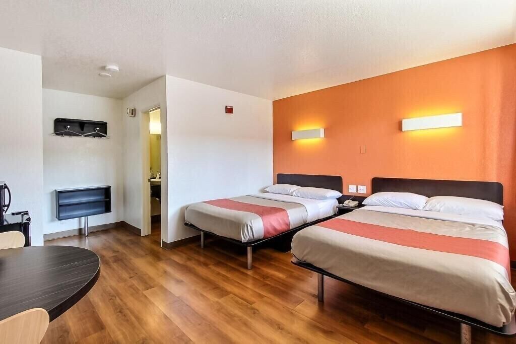 Ett hotellrum med två sängar, ett skrivbord, en stol och en TV.