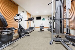 Un gimnasio hotelero con cintas de correr, una banca de pesas y equipo de ejercicio.