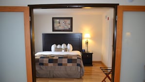 Quarto de hotel com cama, mesa de cabeceira, luminária e cadeira.