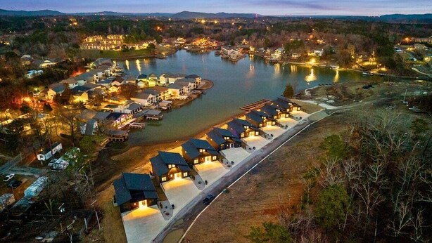 Un complejo turístico junto al lago con varias cabañas, un muelle y un aparcamiento.