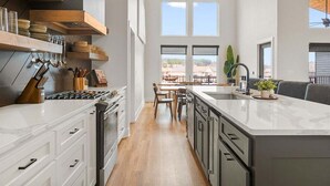 Una cocina moderna con armarios blancos, una isla central y un comedor con vistas.