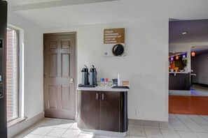 Un espace d’accueil avec une machine à café, un distributeur d’eau et un panneau affiché au mur.