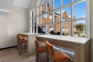 A modern kitchen with a large window, wooden bar counter, and two bar stools. - Park Inn by Radisson San Antonio, TX (San Antonio)