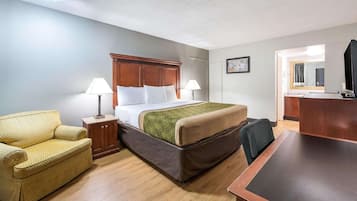 Quarto de hotel com cama, escrivaninha, cadeira, abajur e espelho.