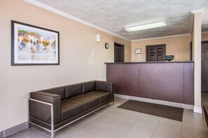 Un área de recepción con un sofá, un mostrador de recepción, un reloj y un cuadro en la pared.