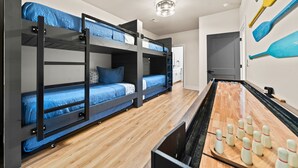 Une chambre avec des lits superposés, une table de billard et des quilles de bowling.