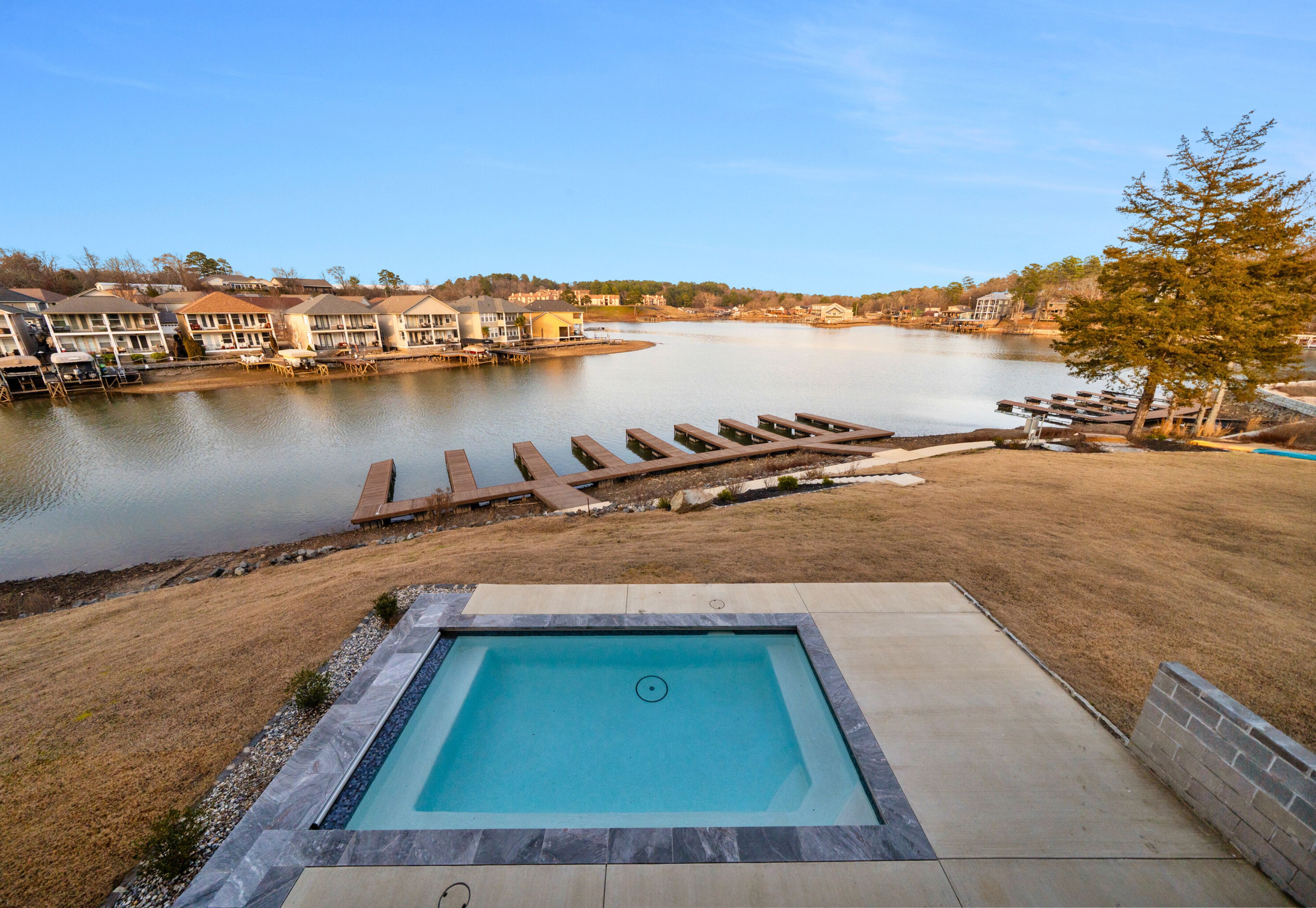 Una piscina con vistas a un lago y casas al fondo.