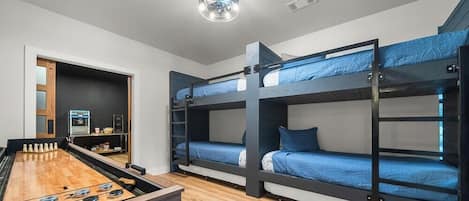 A room with bunk beds, a foosball table, and a kitchenette.