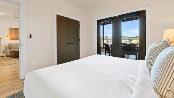 Une chambre d’hôtel avec un grand lit, une porte donnant sur un balcon et une vue sur l’extérieur.