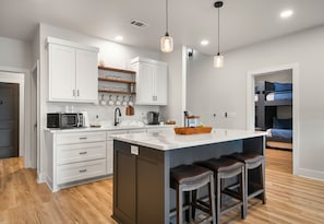 A modern kitchen with white cabinetry, a central island with stools, and pendant lighting. - The Great Escape - 1 (Hot Springs)