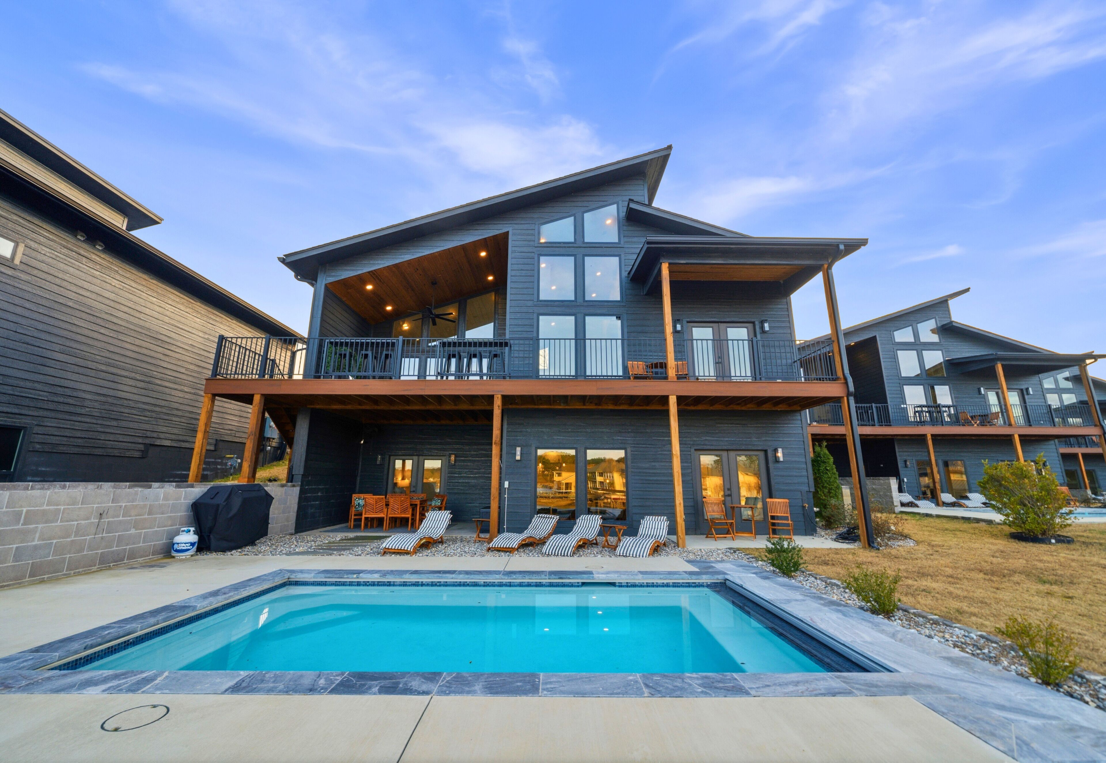 A modern two-story house with a swimming pool, outdoor seating, and a covered patio.