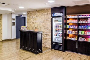 A hotel lobby with a vending machine, a small counter with magazines, and a brick wall. - Comfort Inn Downtown Charleston (Charleston)