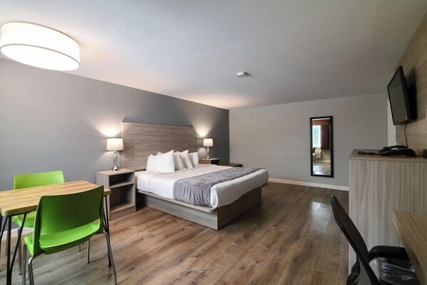 A hotel room with a bed, a desk, a chair, a television, and a mirror. - Knights Inn Danvers (Danvers)