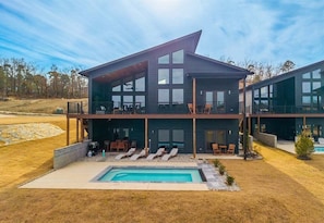 Ein modernes, zweistöckiges Haus mit Swimmingpool, Außenbereich mit Sitzgelegenheiten und einer großen Terrassenfläche.