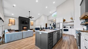A spacious living area with a fireplace, a large island with kitchen appliances, and a modern design. - Private Pool, Dock, Movie Room on Lake Hamilton (Hot Springs)