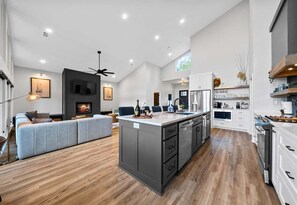 A spacious living area with a fireplace, a large island with kitchen appliances, and a modern design. - Private Pool, Dock, Movie Room on Lake Hamilton (Hot Springs)