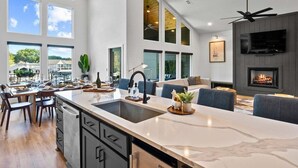 A modern kitchen with a large island, dining area, and a fireplace. - Private Pool, Dock, Movie Room on Lake Hamilton (Hot Springs)