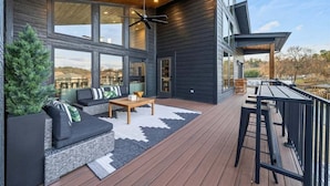 Eine moderne Terrassenanlage im Freien mit einer Sitzecke, einem Couchtisch und einem Essbereich.