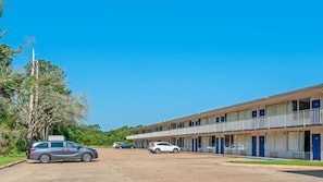 Un motel de dos pisos con varias habitaciones y un estacionamiento.