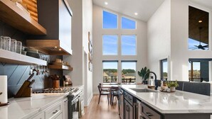 A modern kitchen with a large island, wooden cabinetry, and a view of the outdoors. - Private Pool, Dock, Movie Room on Lake Hamilton (Hot Springs)