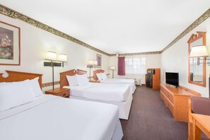 A hotel room with three beds, a TV, a desk, and a dresser. - Days Inn & Suites by Wyndham Marshall (Marshall)