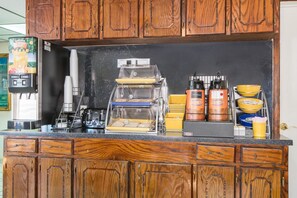 A kitchen counter with a coffee machine, a toaster, and a display case with food items. - Days Inn & Suites by Wyndham Marshall (Marshall)