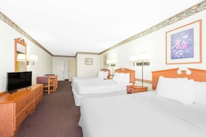 Ein Hotelzimmer mit zwei Betten, einem Fernseher, einem Schreibtisch und einem Sessel.