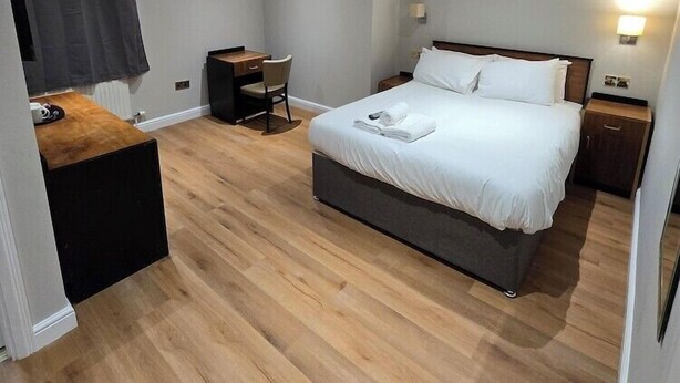 A modern bedroom with a bed, desk, chair, and a small table. - Staindrop Lodge Hotel (Sheffield)